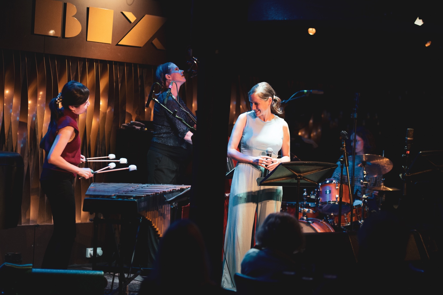 Sara Decker lächelt auf der Bühne im Jazzclub BIX im Gespräch mit ihrer Band