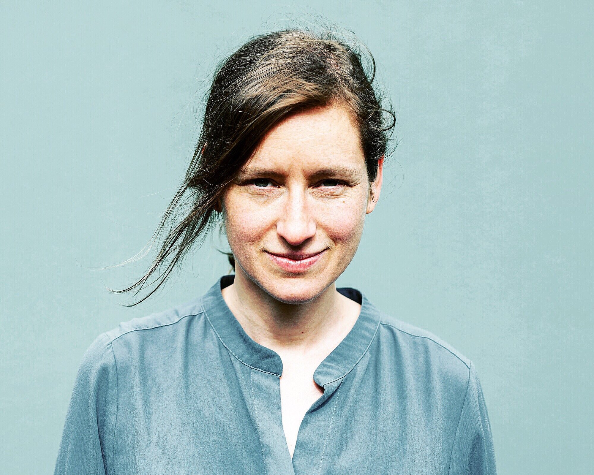 Sara Decker lächelnd vor hellem Hintergrund